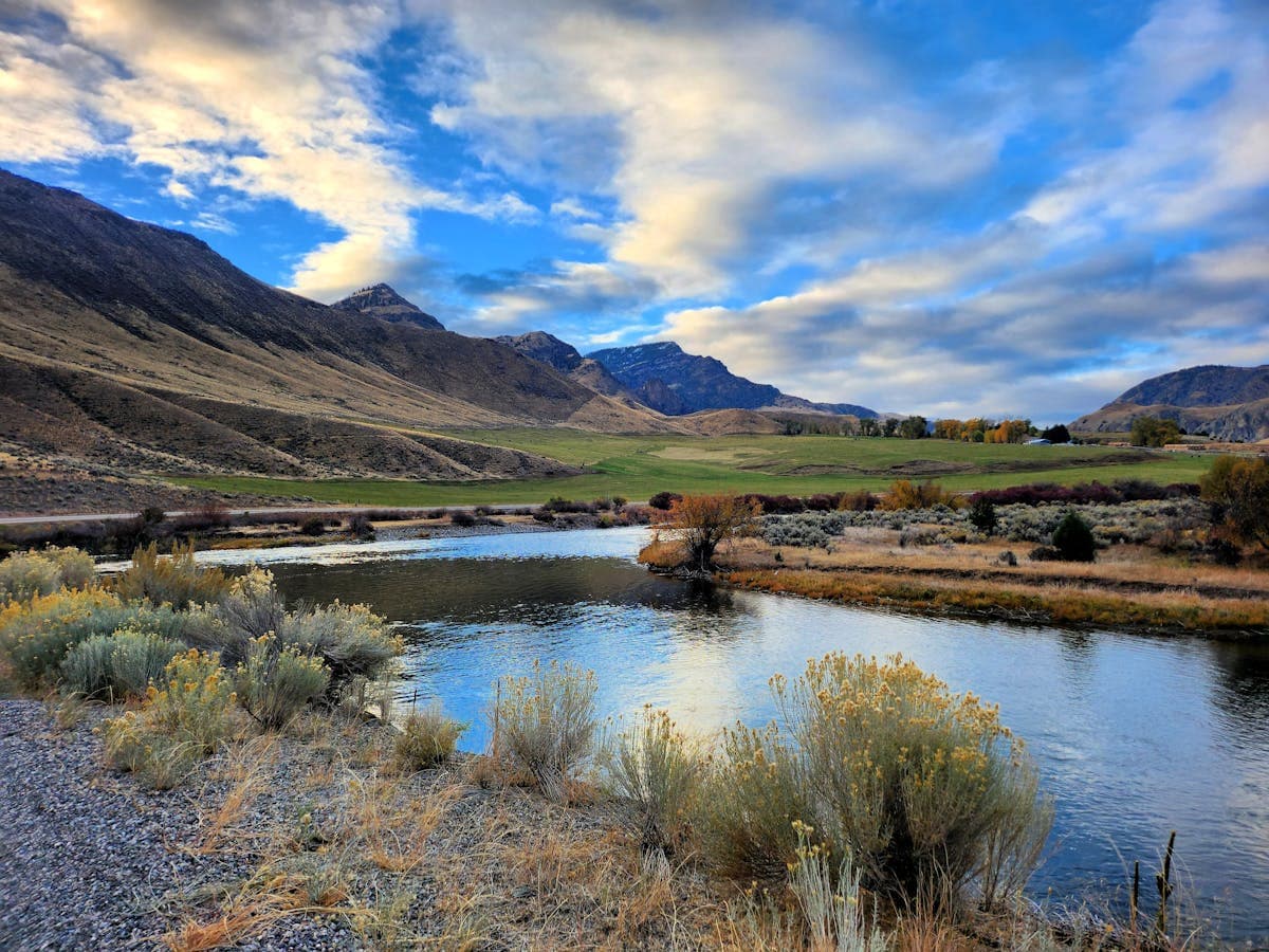 Mountain river winding through a valley with autumn foliage and dramatic sky