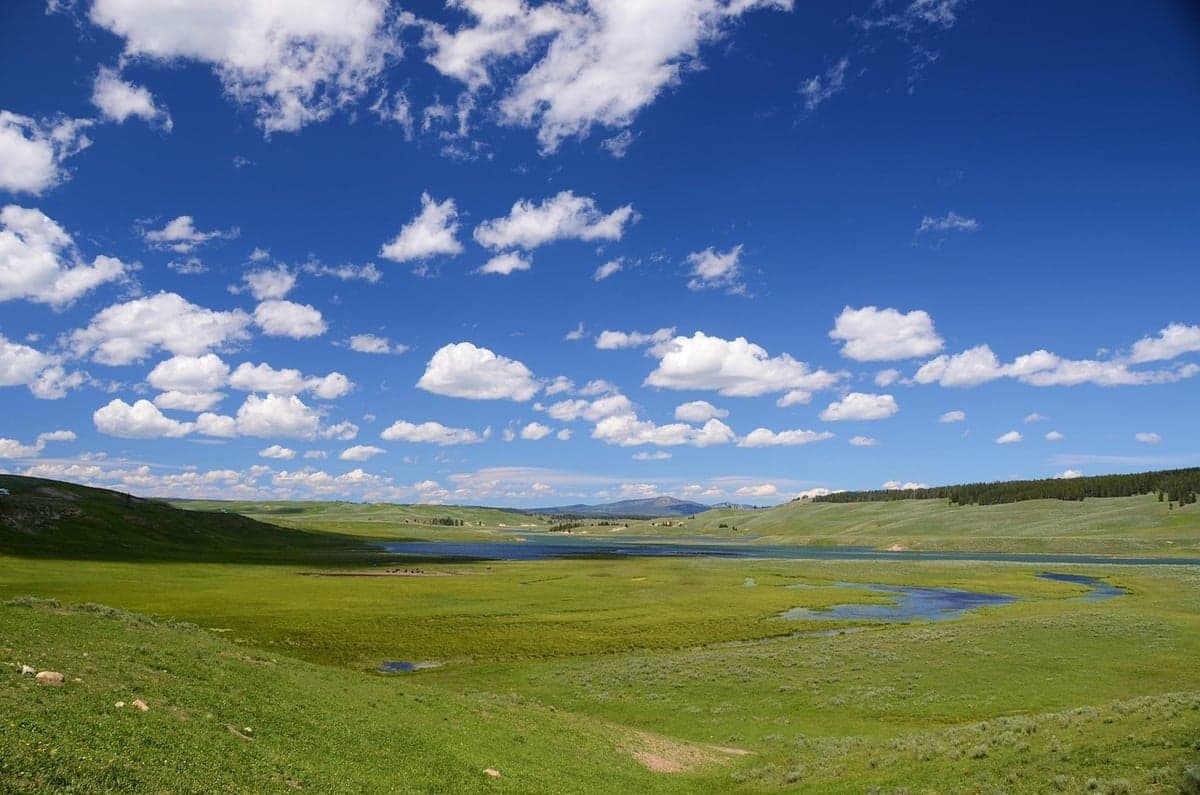 A river winding through a wide open meadow basin with no cover on either bank