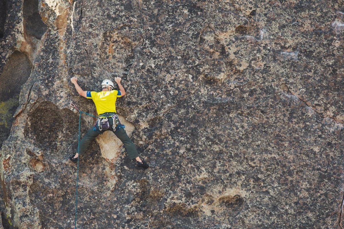 A roped climber working a bolted line on lichen-covered granite. Eleven Mile's domes draw climbers all summer, so expect company at the pullouts and give anyone below a route plenty of room.