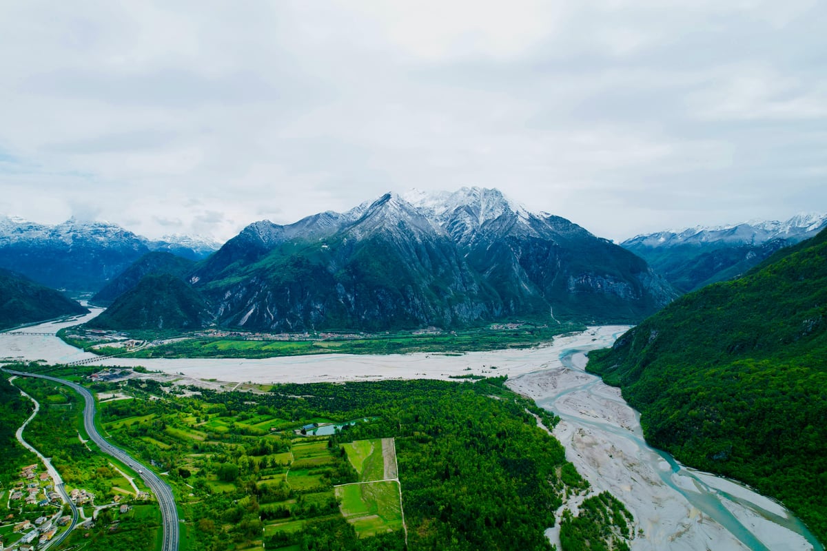 Aerial view of a snowcapped mountain range with a winding river through a green valley
