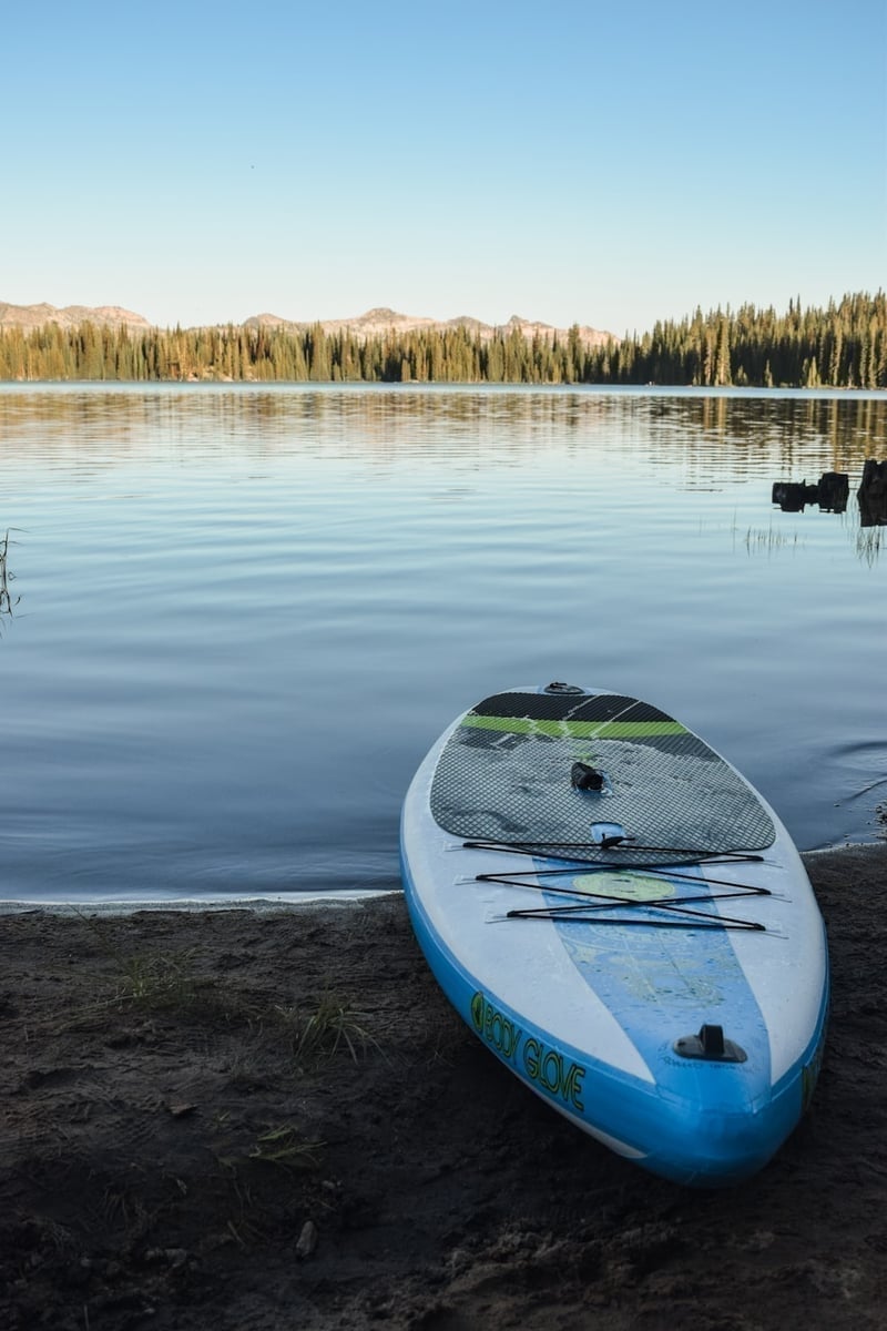 Angler standing on a paddleboard casting a fly rod on a calm mountain lake