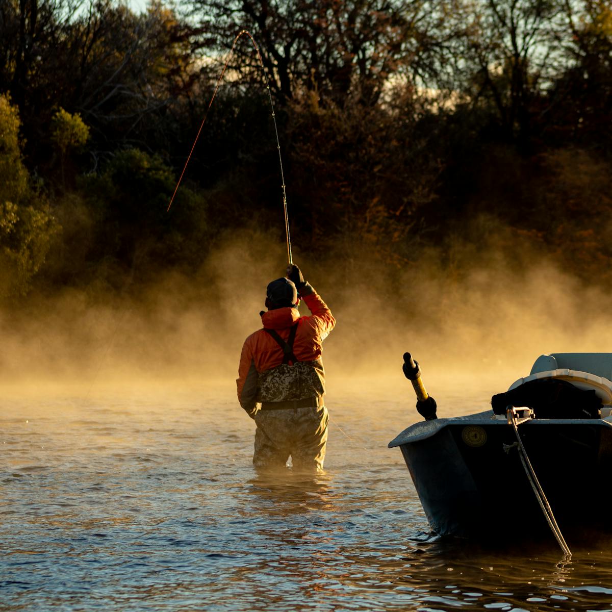 Fly angler casting at dawn on a misty Appalachian tailwater river in Tennessee
